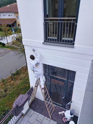 Maler streicht Fassade des Hotels au einer Leiter